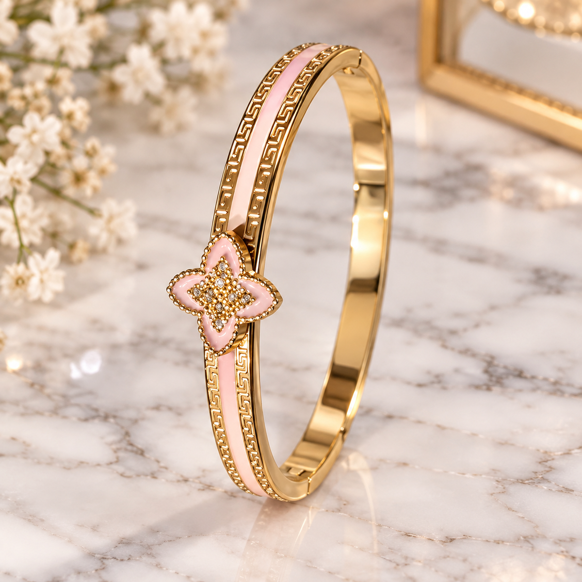 Gold-tone cuff bracelet with a blush pink enamel design and a delicate floral motif
