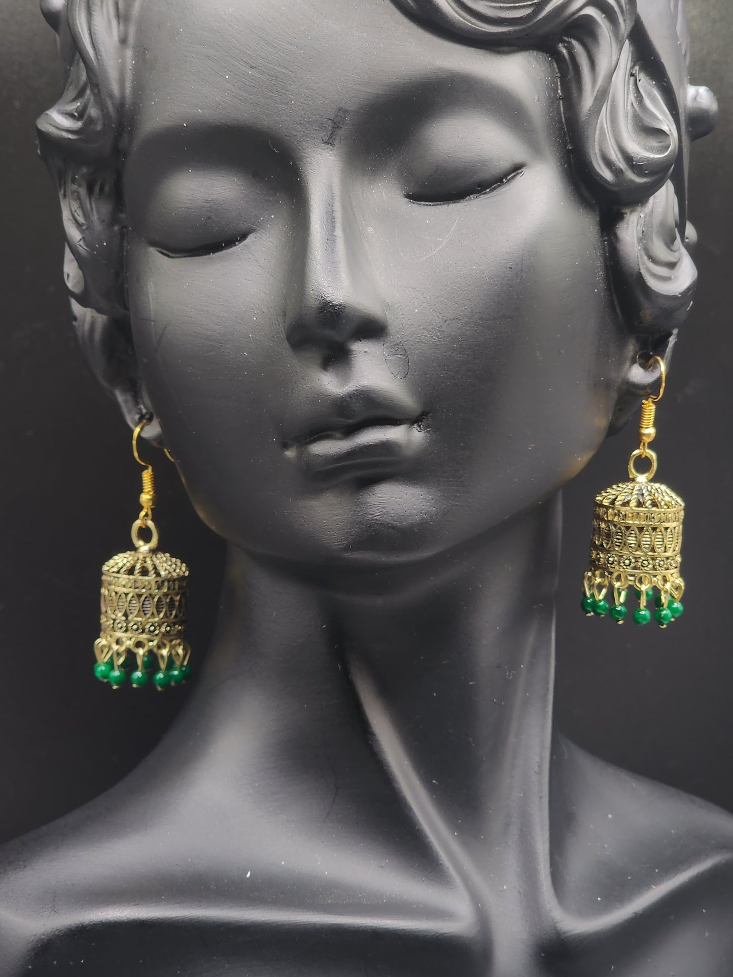 Pskelegance presents these exquisite gold jhumkas, adorned with emerald green drops.