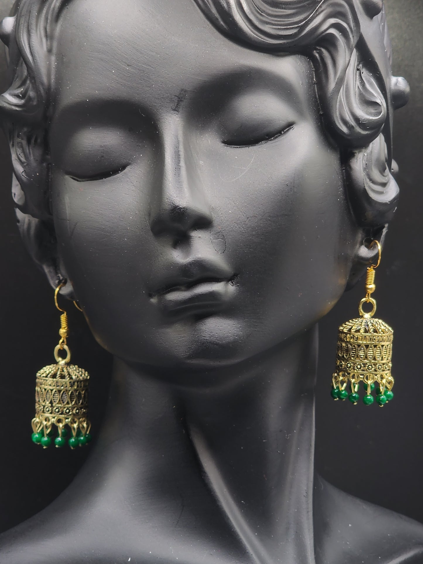 Pskelegance presents these exquisite gold jhumkas, adorned with emerald green drops.